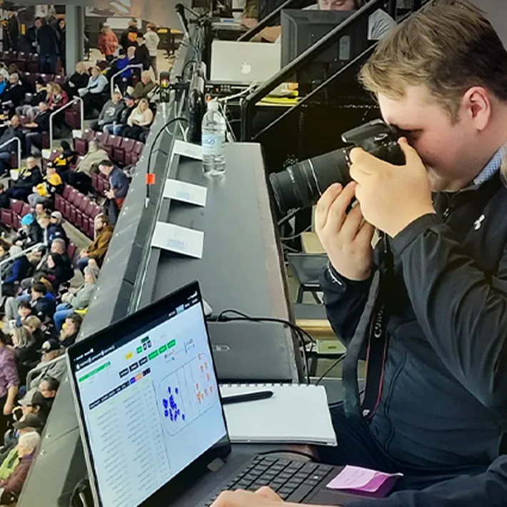 Two students at a Sarnia Sting game taking photos and making notes.